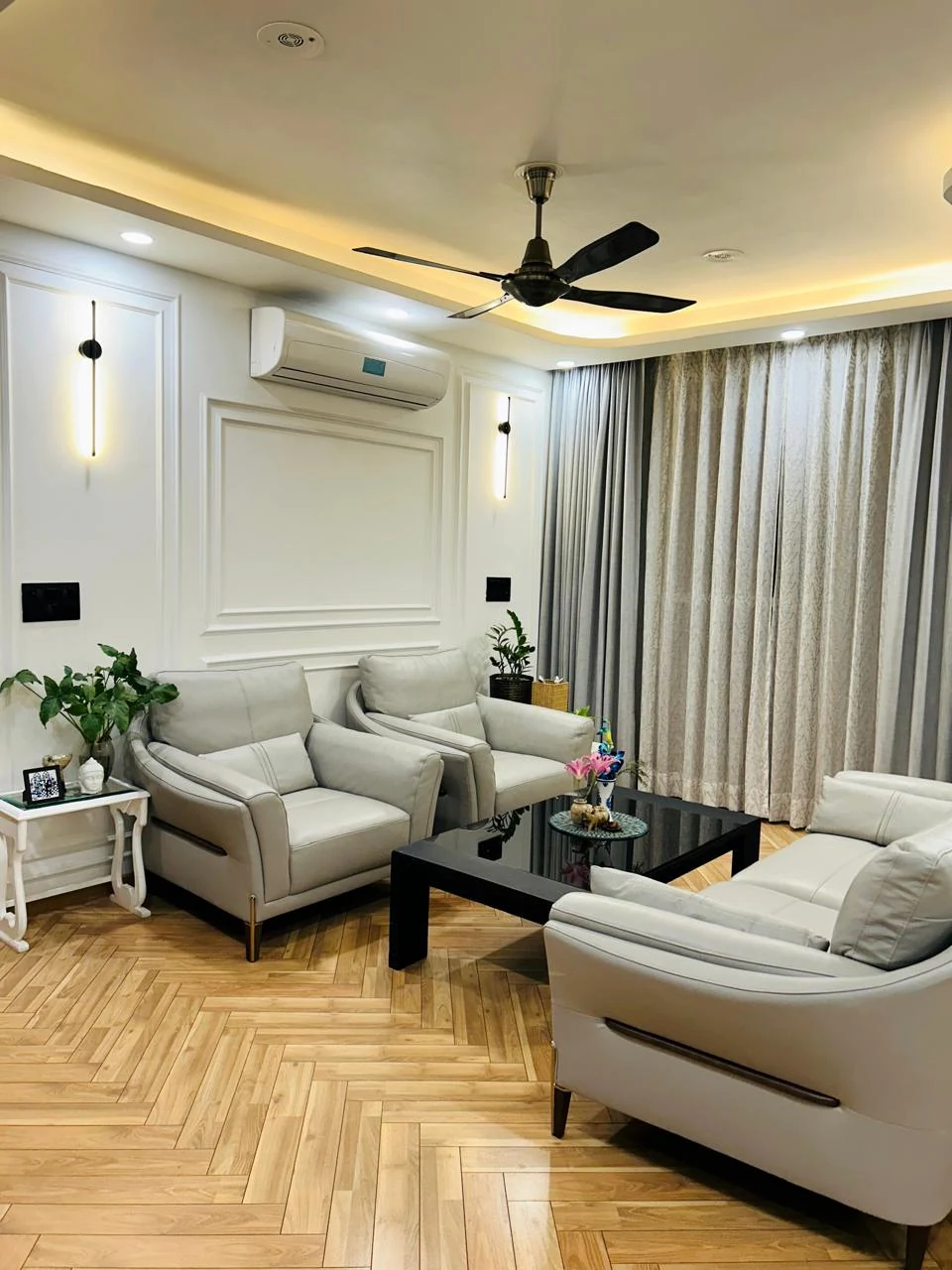 Actual JL STUDIO interior: cream seating, wall mouldings, warm cove lighting and timber-pattern flooring.